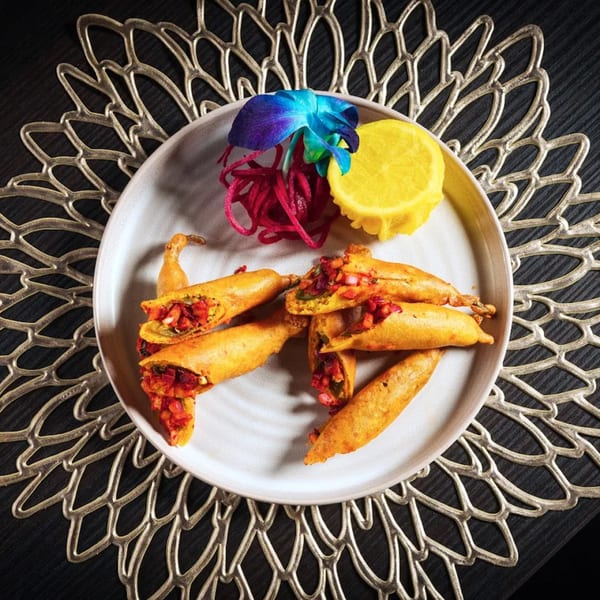 Paheli Modern Indian Cuisine's chili pakora, garnished with a blue orchid, lemon, and pickled onions.